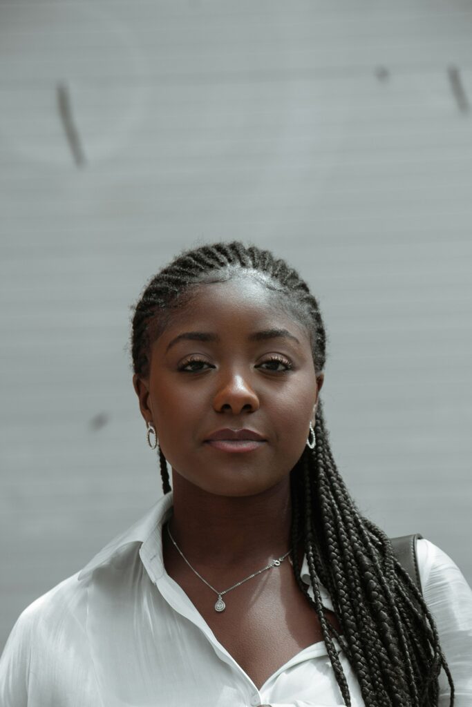 A calm, self-assured woman with long braids in a white shirt